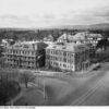 Image: A collection of large, three and four storey buildings clustered together on the corner of two main roads