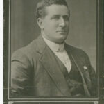 Image: Photographic portrait of a man in a suit jacket, vest and shirt.