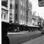 Image: Large department store in Art Deco style dwarfing the adjacent cinema