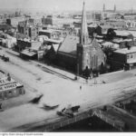 Image: aerial view of stone church with large steeple on street corner