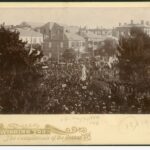 Image: crowds surrounding stone statue of standing man