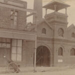 Image: sepia photo of large brick building with arched entrance