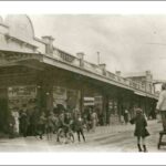 Image: A group of pedestrians and bicyclists congregate in front of a store front. A sign on the store reads 'Pay and Carry Store'