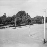 Image: One corner of a large park. A street with a lone gaslight lamp is visible in the foreground