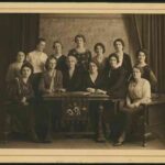 Image: A group of women are gathered around a table. The front row is seated, while those in the back row stand