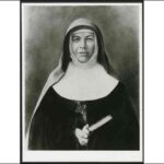 Image: A portrait of a young woman wearing a nun’s habit. She is holding a bible and a crucifix