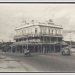 Image: a large, three storey, corner hotel with wrap around balconies on the two upper floors and an ornate parapet