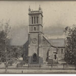 Image: The front of a large stone church building with a tower topped by four spires