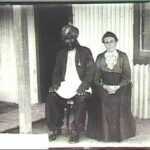 Image: Afghan man and his wife pose for photograph in front of corrugated iron home