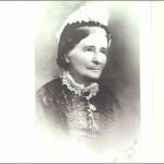 Image: A photographic head-and-shoulders portrait of a middle-aged woman in Victorian attire