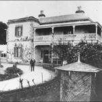 Image: Man stands on curved drive outside a two story house