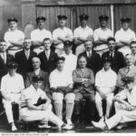 Image: A group of men in cricket uniforms poses for a photograph with other men dressed in suits