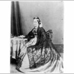 Image: Black and white picture of seated woman in three quarter profile wearing a long dress.