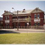 Image: A two-storey brick building with signs advertising the Salvation Army stands near the edge of a park