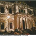 A large, two-storey building at night with images light-projected on its front facade