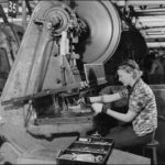 Image: A woman works at a machine to manufacture metal aircraft components