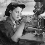 Image: A young woman uses a drill press to manufacture holes in a sheet of metal