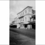 Image: A three storey building with arched windows, decorative plasterwork and a columned portico. A sign painted on its side reads: "The People's Palace"