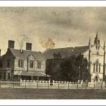 Image: a simple stone church with three spires sits next to a two storey bluestone manse with a verandah and bay window.