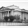 Image: A large, mostly windowless sandstone building fronted by a portico with six columns