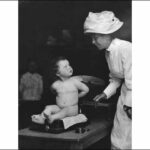 Baby Evangeline Gabriel being being weighed by a nurse 1908