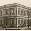 Image: Black and white photograph of a two storied stone building featuring arched windows