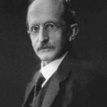 Image: A photographic portrait of a middle-aged man with a moustache and wire-rimmed spectacles