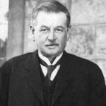 Image: A photographic head-and-shoulders portrait of a moustachioed, middle-aged man in Edwardian attire