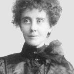 Image: A photographic head-and-shoulders portrait of a woman wearing early Edwardian attire