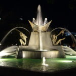 Image: large fountain featuring human figures and birds lit up at night