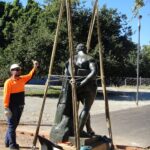 Image: man in hard hat and hi-vis supervising statue being lifted using hoist