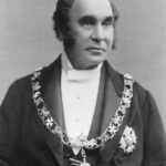 Image: Black and white photograph of man wearing formal clothes and livery collar