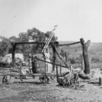 Image: Young boy standing outside among collection of farm machinery