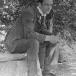 Image: black and white photograph of a man sitting in garden