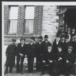 The German consul sitting surrounded by his welcoming party at the front of a house in Hahndorf