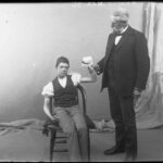 Image: seated boy with bandaged hand held by standing man