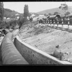 Image: Large water pipes on ground and buildings in the distance