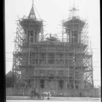 Image: A large stone church with twin spires is under construction and surrounded by scaffolding