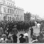 Image: crowd of people in front of large three story building