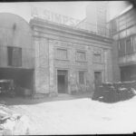 Image: A two-storey bluestone building, the windows in the upper floor of which have been blocked up with stone and/or brick. A sign above the building reads A. Simpson & Son