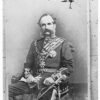 Image: A photographic portrait of a middle-aged Caucasian man in full military dress uniform. He has large mutton-chop sideburns and a bushy moustache