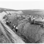 Image: Men digging a deep trench through bare paddocks