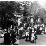 Image: crowd of children walking through large wrought iron gates