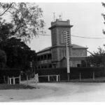 Image : Old stone building with tower and dirt driveway.