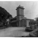 Image : Stone two story building with garden and sweeping driveway.