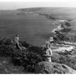 Image: Two women standing on rocks overlooking a rugged coastline