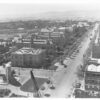 Image: Image: Black and white photograph of a tree lined boulevard, as viewed from the roof of a building. The buildings lining one side of the road are grand stone constructions and are surrounded by formal gardens.