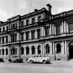 Image: three cars parked in front of long, three story building