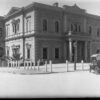 Image: An Italianate style two storey rendered building with columned portico and low pitched roof. The ground floor windows are rectangular with simple arced pediments, the upper floor windows are arched with decorative stonework to square them off.