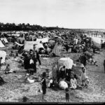 Image: Crowds of people on a beach with an assortment of tents